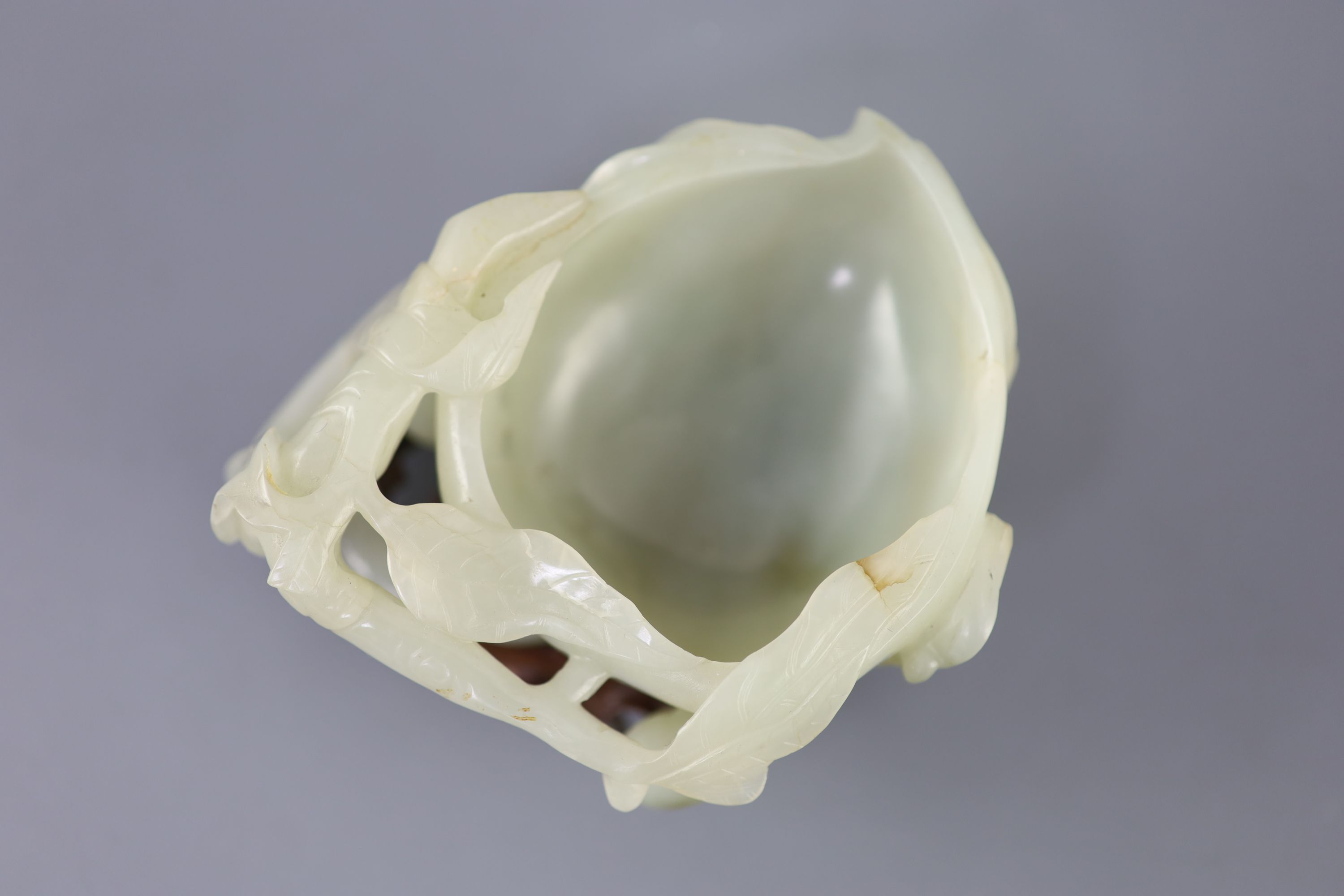 A Chinese pale celadon jade peach brush washer, 17th/18th century 11.3cm at widest point, wood stand